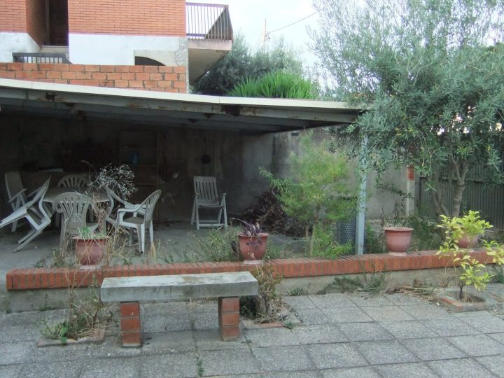 Patio antes de la reforma: porche metálico deteriorado y pavimento antiguo